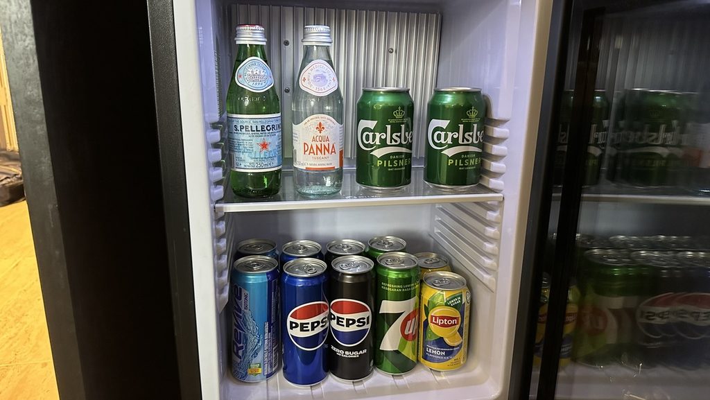 客室の冷蔵庫に並ぶ瓶入りの水と缶入りの飲み物