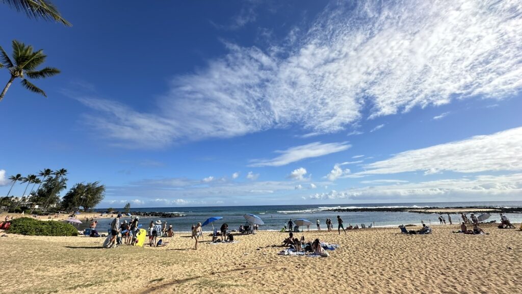 青空の下で多くの人が過ごすPoipu Beach Park