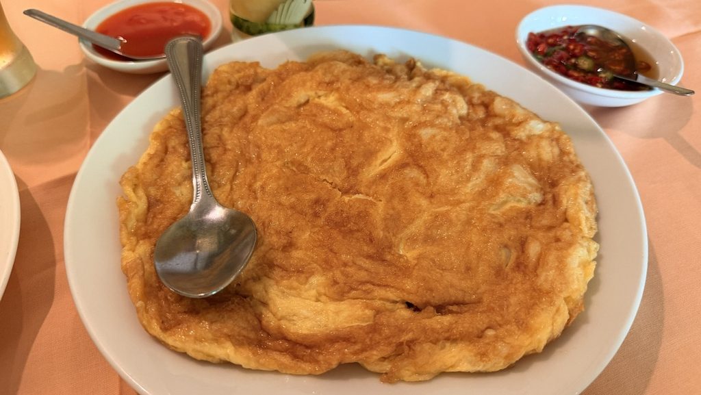 大きな丸い皿に広がるカニ身入りオムレツ