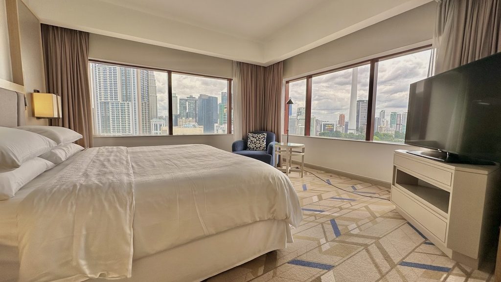 角窓に囲まれたクラブラウンジアクセス付き1ベッドルームスイートのベッドルーム